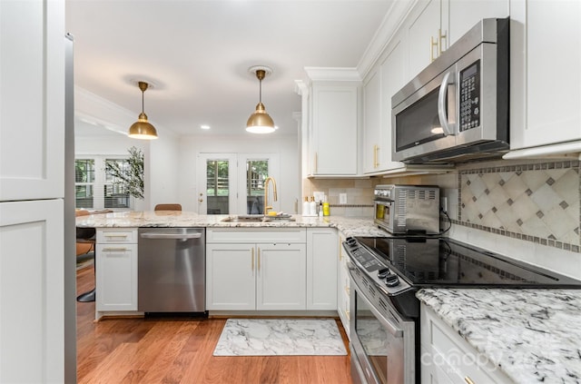 3106 Windstream Ct, Charlotte, NC 28210 - kitchen featuring stainless steel appliances, white cabinets, a peninsula, light wood-style flooring, and crown molding