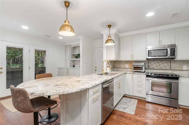 3106 Windstream Ct, Charlotte, NC 28210 - kitchen featuring appliances with stainless steel finishes, a peninsula, light wood finished floors, tasteful backsplash, and ornamental molding
