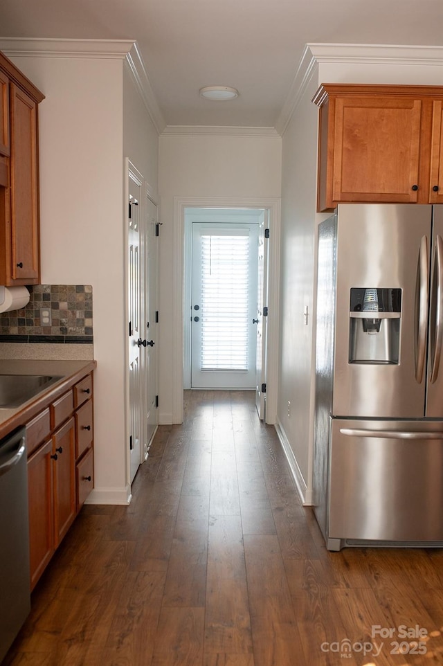 4500 Sages Ave, Indian Trail, NC 28079 - kitchen featuring appliances with stainless steel finishes, brown cabinetry, crown molding, decorative backsplash, and dark wood-style floors