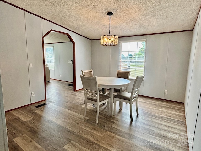2268 Arrowwood Dr, Hickory, NC 28601 - dining area featuring crown molding, a textured ceiling, arched walkways, wood finished floors, and a chandelier