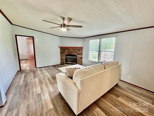 2268 Arrowwood Dr, Hickory, NC 28601 - living room featuring ornamental molding, a ceiling fan, a textured ceiling, wood finished floors, and a stone fireplace