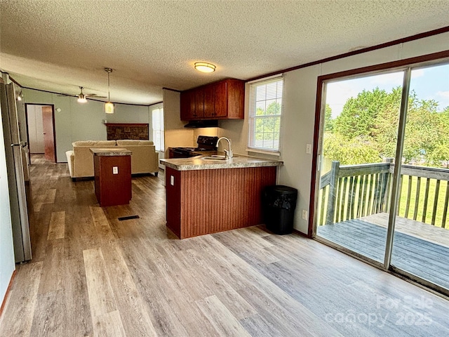 2268 Arrowwood Dr, Hickory, NC 28601 - kitchen with black gas range, wood finished floors, a textured ceiling, open floor plan, and a peninsula