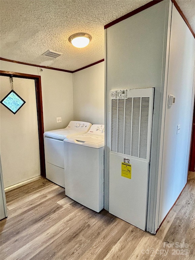2268 Arrowwood Dr, Hickory, NC 28601 - washroom featuring independent washer and dryer, a heating unit, light wood-type flooring, a textured ceiling, and crown molding
