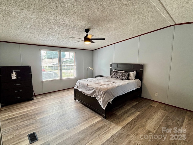 2268 Arrowwood Dr, Hickory, NC 28601 - bedroom with a decorative wall, crown molding, a textured ceiling, light wood-style flooring, and ceiling fan
