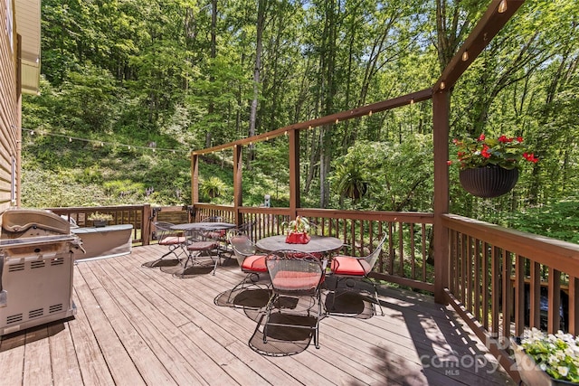 747 Bear Cove Cir, Bryson City, NC 28713 - wooden terrace with outdoor dining area, a grill, and a view of trees