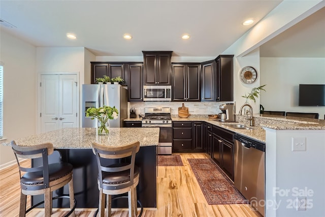 1727 Evergreen Dr, Charlotte, NC 28208 - kitchen with stainless steel appliances, light wood-style floors, light stone counters, a kitchen island, and backsplash