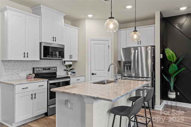 3740 Backwater St, Concord, NC 28027 - kitchen featuring appliances with stainless steel finishes, light wood-type flooring, white cabinets, backsplash, and hanging light fixtures
