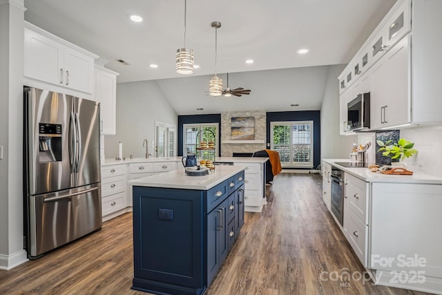 2607 Old Ashworth Ln NW, Concord, NC 28027 - kitchen featuring stainless steel appliances, blue cabinets, light countertops, a stone fireplace, and dark wood finished floors