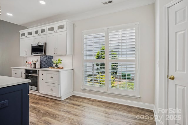 2607 Old Ashworth Ln NW, Concord, NC 28027 - kitchen with stainless steel appliances, decorative backsplash, light countertops, light wood-style floors, and glass insert cabinets