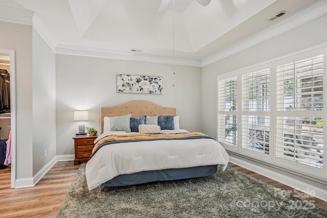 2607 Old Ashworth Ln NW, Concord, NC 28027 - bedroom with wood finished floors, a spacious closet, ornamental molding, a tray ceiling, and ceiling fan