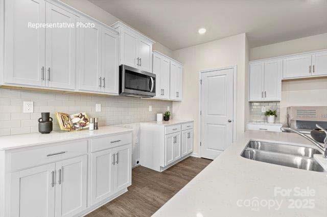 9235 Poquoson Dr, Gastonia, NC 28056 - kitchen with stainless steel microwave, white cabinets, dark wood finished floors, and light countertops