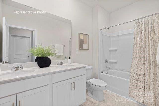 9235 Poquoson Dr, Gastonia, NC 28056 - full bathroom featuring shower / bath combination with curtain, double vanity, and tile patterned flooring