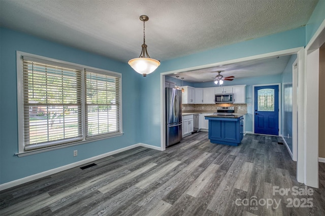 207 Valdese Dr, Morganton, NC 28655 - kitchen with stainless steel appliances, white cabinets, dark wood-style floors, decorative backsplash, and a textured ceiling