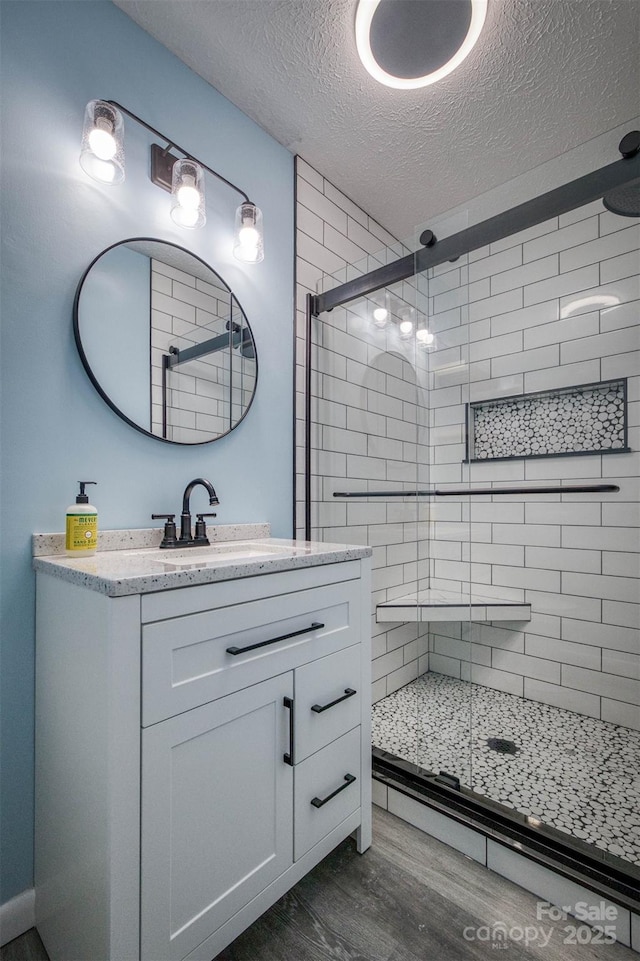 207 Valdese Dr, Morganton, NC 28655 - full bathroom with wood finished floors, a textured ceiling, a shower stall, and vanity