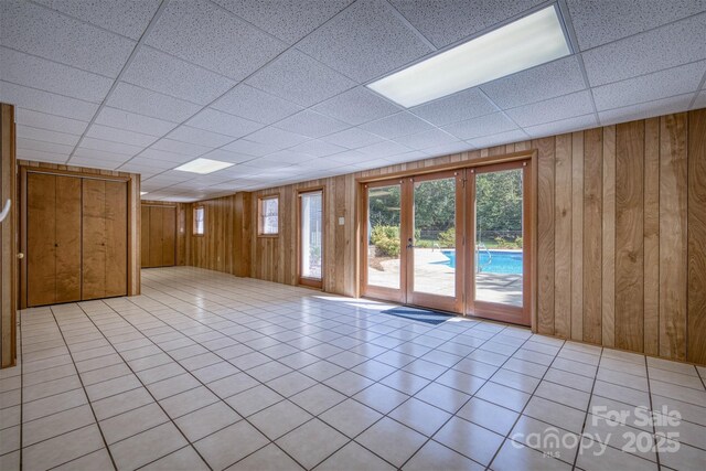 207 Valdese Dr, Morganton, NC 28655 - tiled empty room featuring wooden walls, french doors, and a drop ceiling
