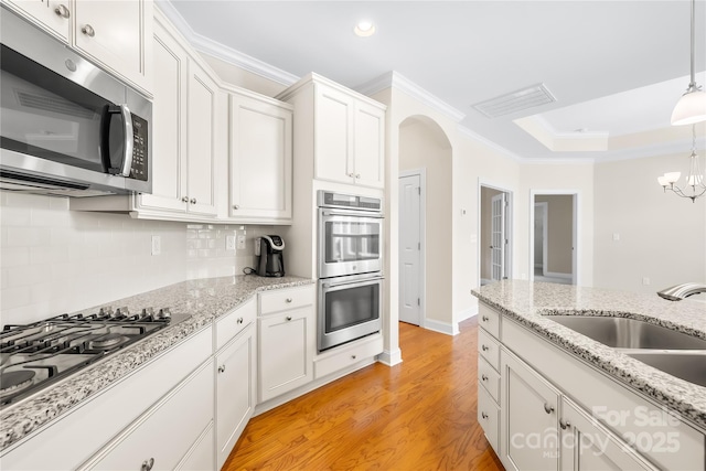135 Valleymist Ln, Mooresville, NC 28117 - kitchen with appliances with stainless steel finishes, crown molding, arched walkways, white cabinetry, and decorative backsplash