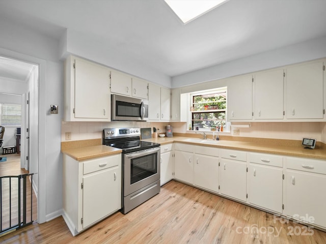 312 Garrison Dr, Albemarle, NC 28001 - kitchen with appliances with stainless steel finishes, light wood-style floors, light countertops, and decorative backsplash