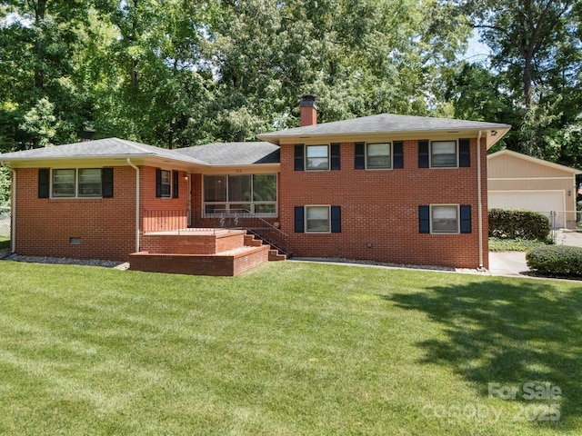 312 Garrison Dr, Albemarle, NC 28001 - tri-level home with a front yard, a chimney, brick siding, an outbuilding, and roof with shingles