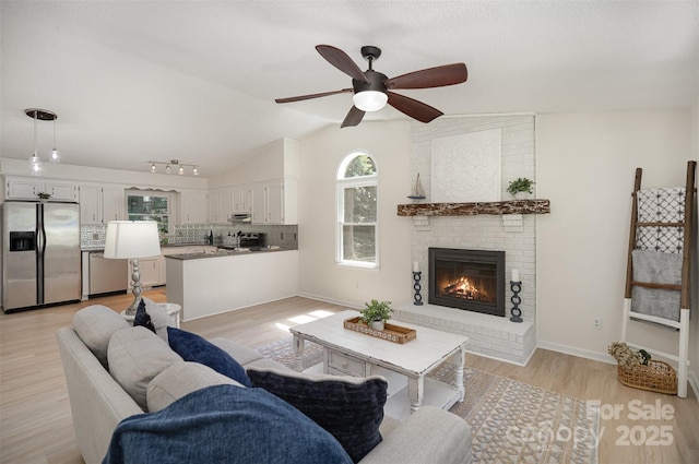 256 Timberland Loop, Mooresville, NC 28115 - living area featuring a brick fireplace, a ceiling fan, light wood finished floors, and vaulted ceiling