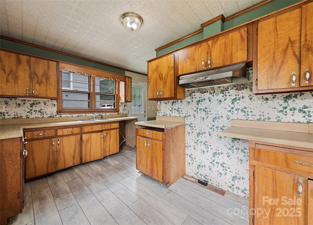 3575 Dellwood Rd, Waynesville, NC 28786 - kitchen featuring under cabinet range hood, wallpapered walls, light wood-style flooring, brown cabinets, and light countertops