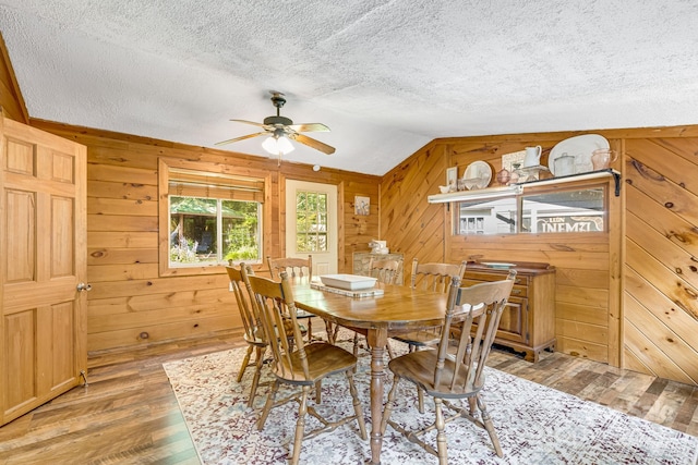 19 Timbers Edge Ln, Fairview, NC 28730 - dining room featuring ceiling fan, a textured ceiling, light wood finished floors, lofted ceiling, and wooden walls