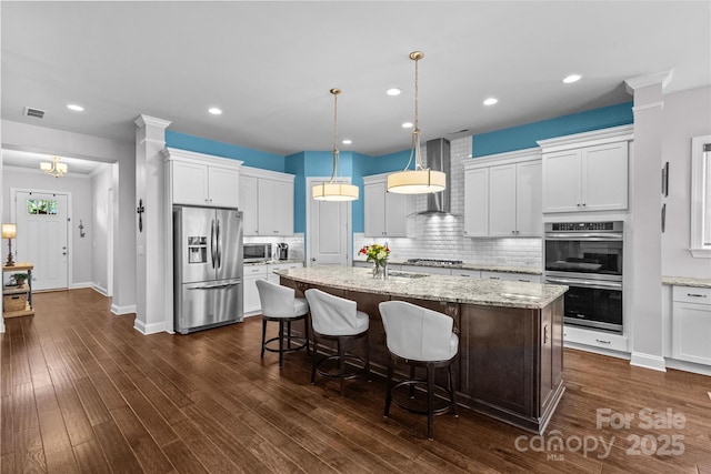 4928 Providence Country Club Dr, Charlotte, NC 28277 - kitchen featuring stainless steel appliances, wall chimney exhaust hood, a kitchen island with sink, backsplash, and white cabinets