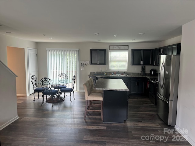 1076 Tangle Ridge Dr SE, Concord, NC 28025 - kitchen with stainless steel appliances, a kitchen island, a kitchen bar, dark wood-style flooring, and dark cabinets