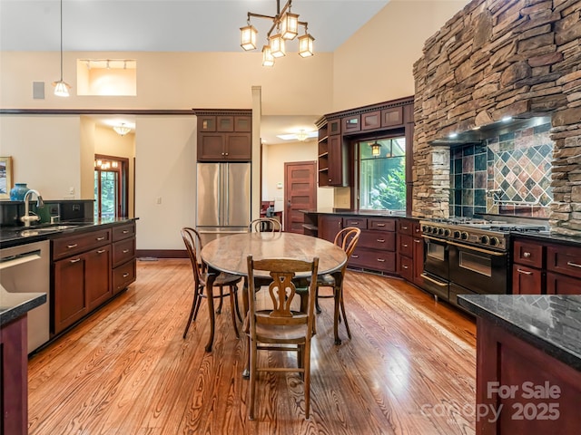 935 Whites Lake Blvd, Saluda, NC 28773 - kitchen with stainless steel appliances, light wood finished floors, pendant lighting, open shelves, and a towering ceiling