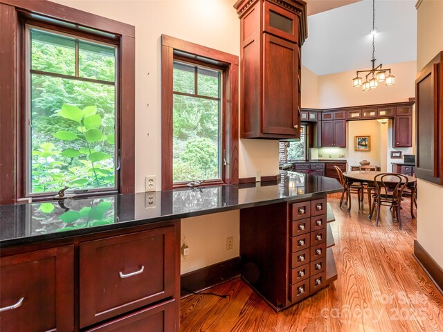 935 Whites Lake Blvd, Saluda, NC 28773 - kitchen featuring plenty of natural light, light wood-type flooring, a chandelier, dark stone counters, and a high ceiling
