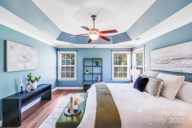 4525 Chestwood Ct, Rock Hill, SC 29732 - bedroom featuring a tray ceiling, multiple windows, wood finished floors, ornamental molding, and ceiling fan