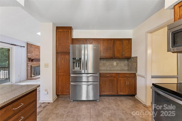 4601 Bournewood Ln, Charlotte, NC 28226 - kitchen with stainless steel appliances, backsplash, brown cabinetry, light stone counters, and a brick fireplace