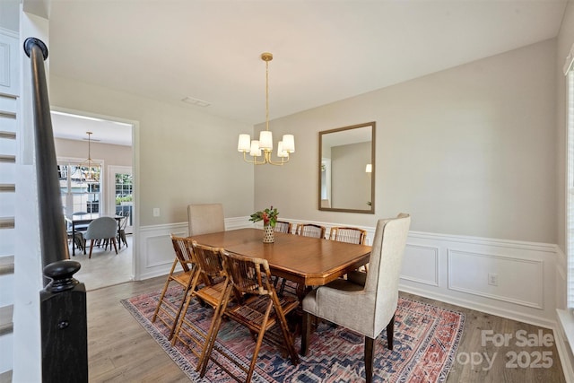 7930 Lancken Dr, Charlotte, NC 28277 - dining space featuring a chandelier, wainscoting, light wood-style floors, and a decorative wall