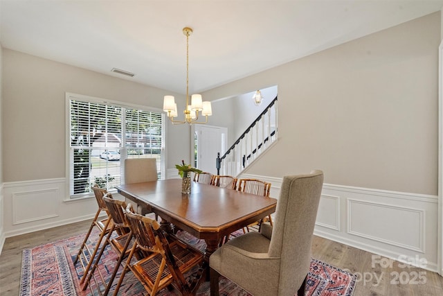 7930 Lancken Dr, Charlotte, NC 28277 - dining room with a chandelier, light wood-style floors, a wainscoted wall, stairs, and a decorative wall