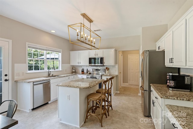 7930 Lancken Dr, Charlotte, NC 28277 - kitchen with appliances with stainless steel finishes, white cabinets, a kitchen island, light stone counters, and recessed lighting