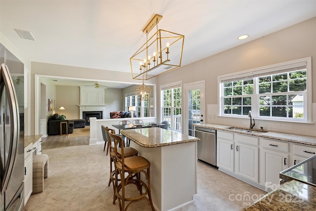 7930 Lancken Dr, Charlotte, NC 28277 - kitchen with appliances with stainless steel finishes, a center island, light stone countertops, a fireplace, and pendant lighting