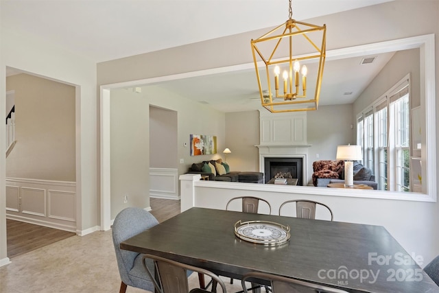 7930 Lancken Dr, Charlotte, NC 28277 - dining area with a chandelier, a fireplace, a wainscoted wall, and a decorative wall