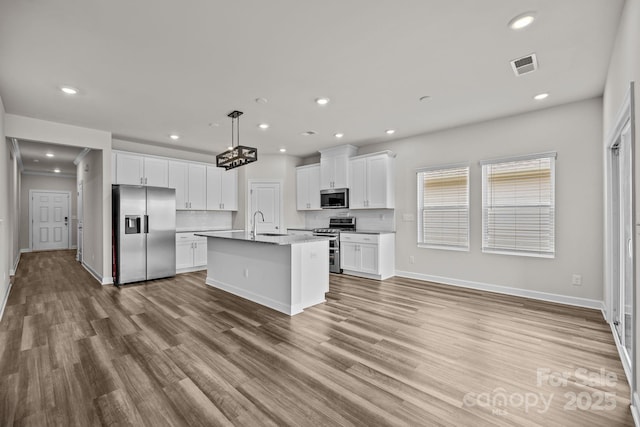 4502 Bright Rd, Charlotte, NC 28214 - kitchen with stainless steel appliances, white cabinets, recessed lighting, wood finished floors, and a center island with sink