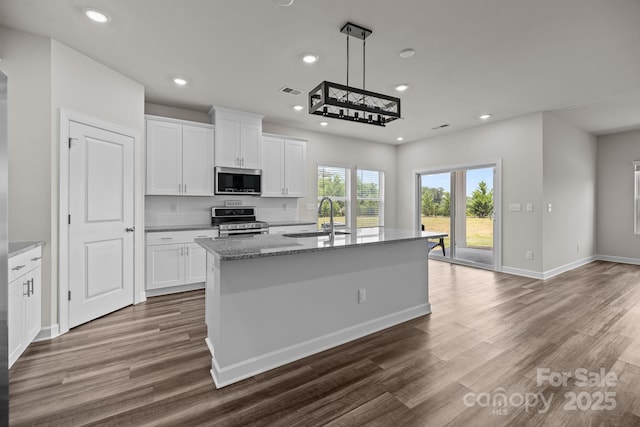 4502 Bright Rd, Charlotte, NC 28214 - kitchen with appliances with stainless steel finishes, dark wood-style floors, light stone countertops, recessed lighting, and a center island with sink