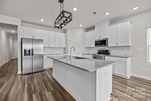4502 Bright Rd, Charlotte, NC 28214 - kitchen with appliances with stainless steel finishes, a kitchen island with sink, dark wood-type flooring, white cabinets, and decorative backsplash