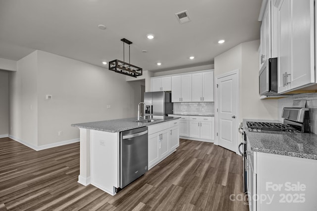 4502 Bright Rd, Charlotte, NC 28214 - kitchen featuring appliances with stainless steel finishes, dark wood finished floors, decorative backsplash, an island with sink, and recessed lighting