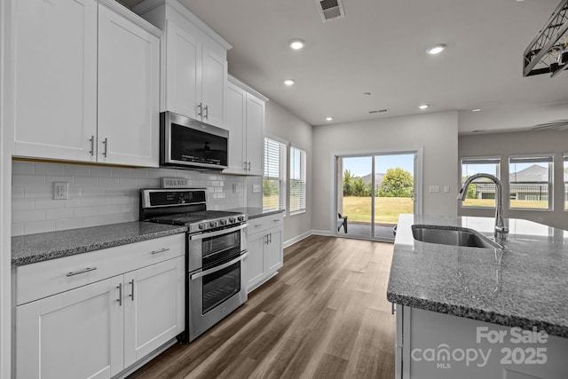 4502 Bright Rd, Charlotte, NC 28214 - kitchen with appliances with stainless steel finishes, recessed lighting, dark stone countertops, backsplash, and wood finished floors