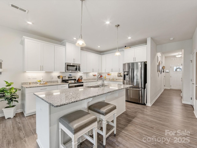510 Park Meadows Dr, Matthews, NC 28104 - kitchen featuring appliances with stainless steel finishes, light wood-style floors, an island with sink, white cabinetry, and recessed lighting