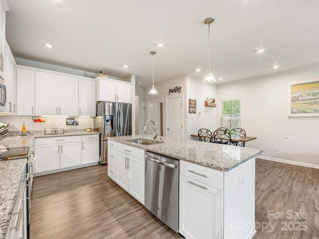 510 Park Meadows Dr, Matthews, NC 28104 - kitchen featuring appliances with stainless steel finishes, wood finished floors, a kitchen island with sink, recessed lighting, and white cabinets
