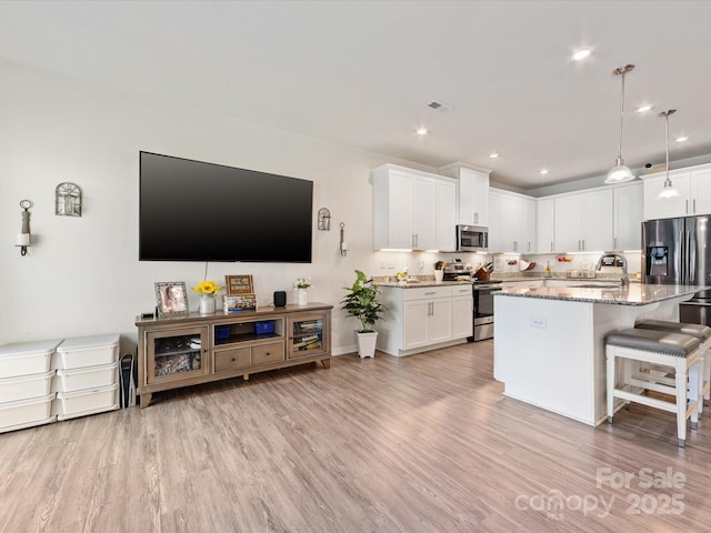 510 Park Meadows Dr, Matthews, NC 28104 - kitchen with appliances with stainless steel finishes, light stone countertops, a breakfast bar area, light wood-style flooring, and recessed lighting