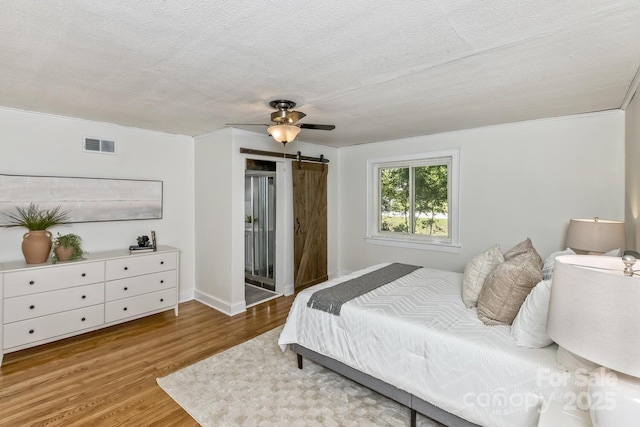 39 Nix Rd, Hendersonville, NC 28792 - bedroom featuring wood finished floors, a barn door, access to outside, a textured ceiling, and ceiling fan