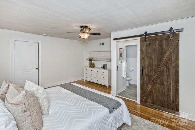 39 Nix Rd, Hendersonville, NC 28792 - bedroom with a barn door, wood finished floors, a textured ceiling, ensuite bath, and a ceiling fan