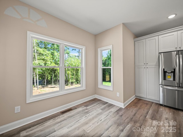 205 S Hill Ave, Albemarle, NC 28001 - kitchen with stainless steel fridge, plenty of natural light, light wood-style flooring, white cabinetry, and recessed lighting
