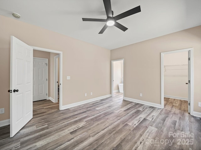 205 S Hill Ave, Albemarle, NC 28001 - unfurnished bedroom featuring wood finished floors, a walk in closet, a ceiling fan, a closet, and ensuite bathroom