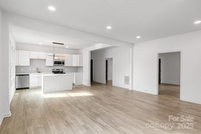 250 Franklin Ave NW, Concord, NC 28025 - kitchen featuring appliances with stainless steel finishes, open floor plan, light countertops, white cabinets, and light wood-style floors