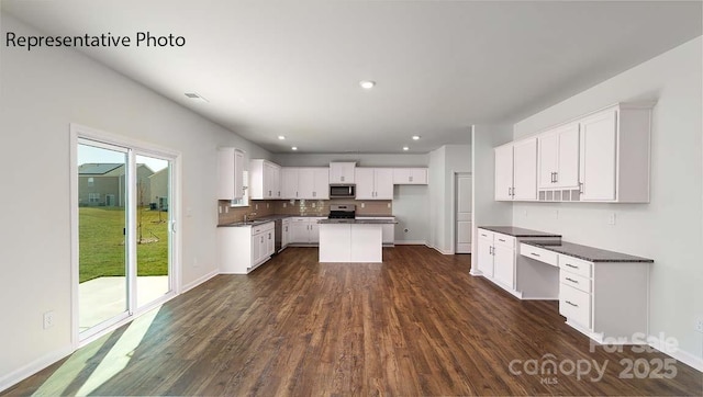 9223 Poquoson Dr, Gastonia, NC 28056 - kitchen featuring stainless steel appliances, dark wood-type flooring, dark countertops, white cabinets, and backsplash